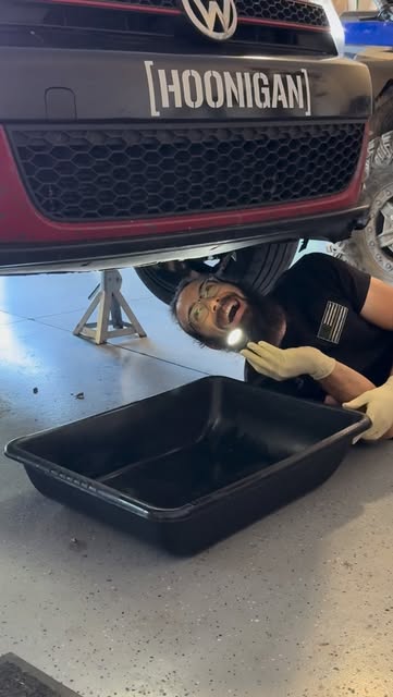 Mechanic checking under a car with a headlamp during service